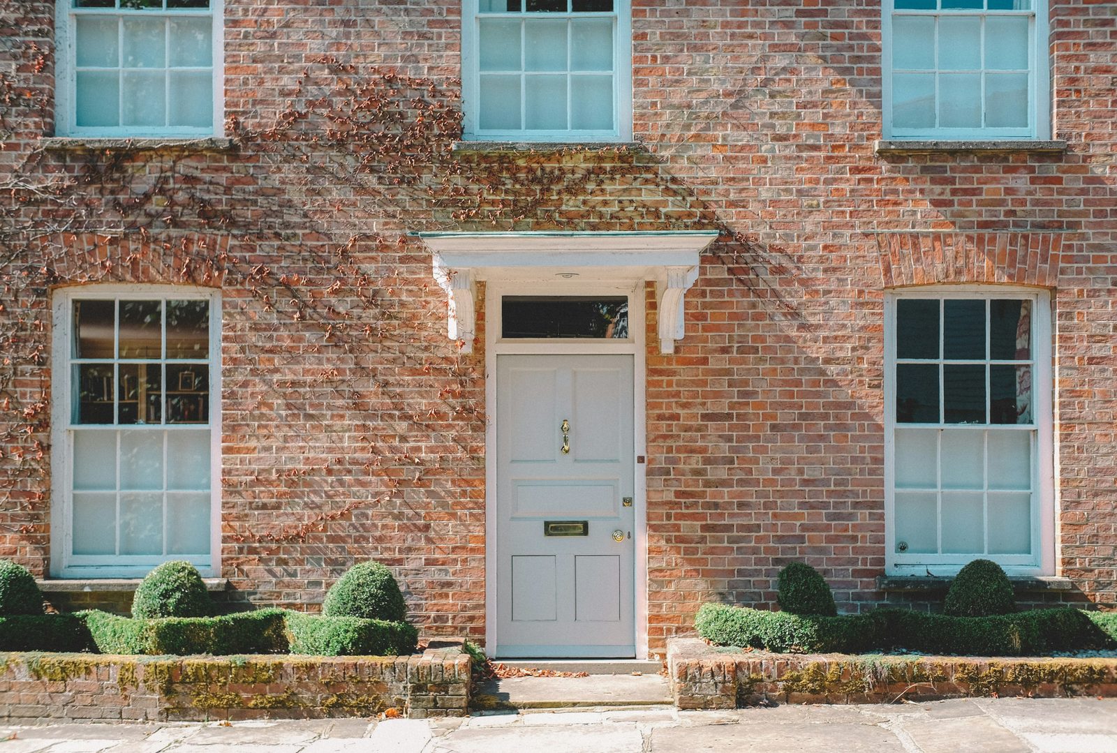 Colonial brick home with a white entry door and double-hung windows